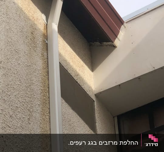 מרזב לבן מחובר לגג אדום